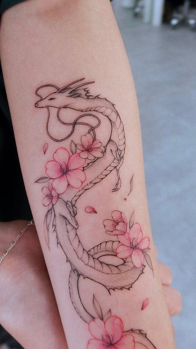 Dragon tattoo with pink cherry blossoms on a person's forearm