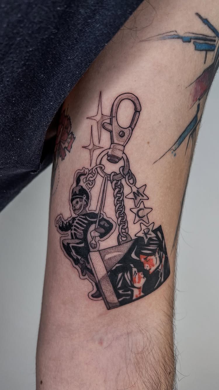 Keychain tattoo with a skeleton, stars, and a red and black portrait charm.