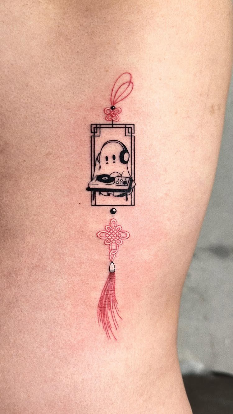 Ghost DJ tattoo with red decorative knots and a tassel on skin