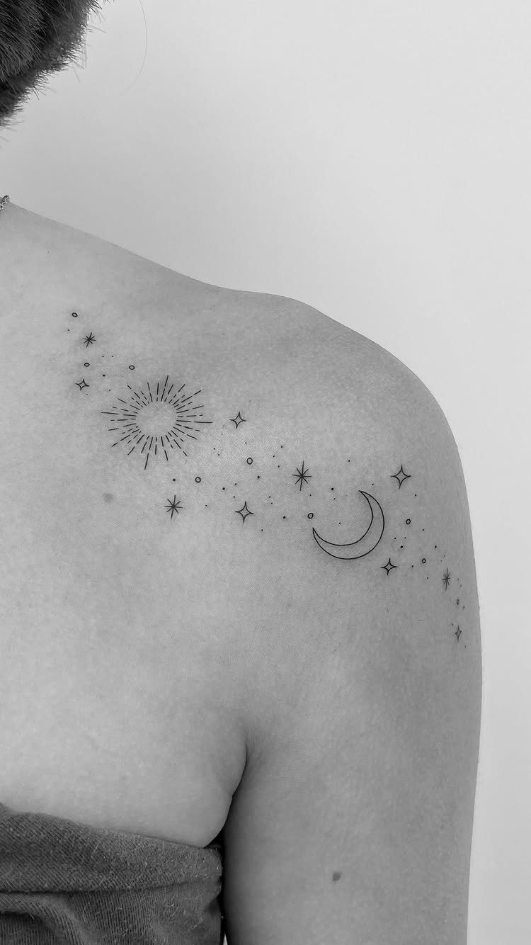 Crescent moon, sun, and stars tattoo on a person's shoulder in black and white.