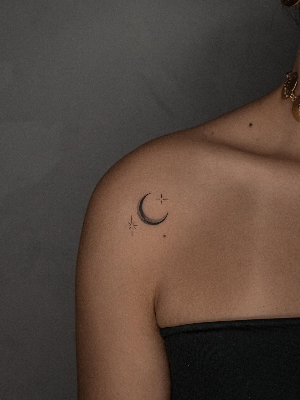 Crescent moon and tiny stars tattoo on a person's shoulder
