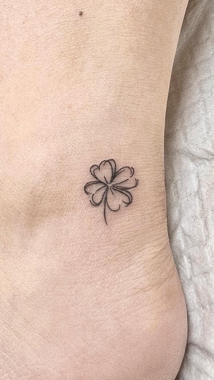Small black ink four leaf clover tattoo on fair skin.