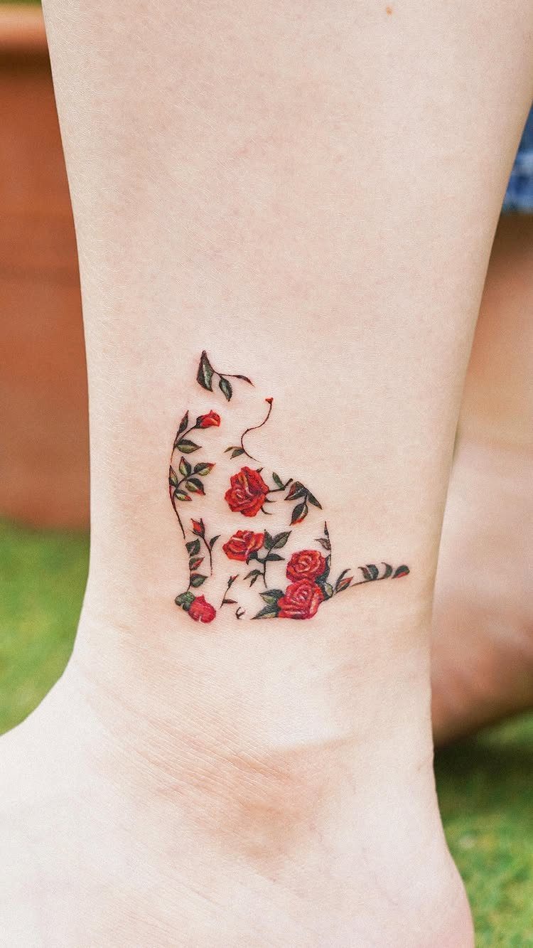 Cat silhouette tattoo made of small red roses on a person's ankle.
