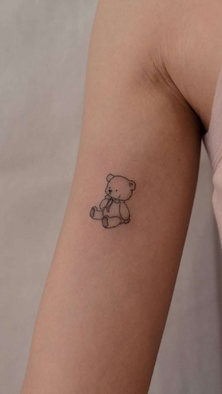 Small teddy bear tattoo in black ink on a person's inner arm.