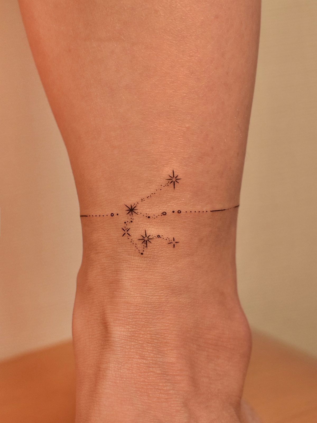 26 Small Pretty Tattoos for Butterflies, Stars, and More 16 Constellation tattoo with small stars and dots wrapped around a person's ankle.