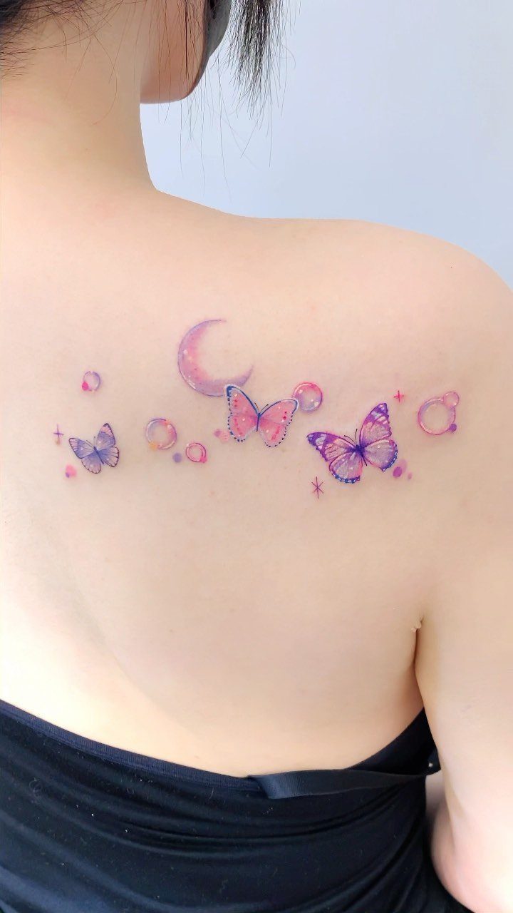 26 Small Pretty Tattoos for Butterflies, Stars, and More 1 Colorful butterfly tattoos with a crescent moon on a person's upper back shoulder.