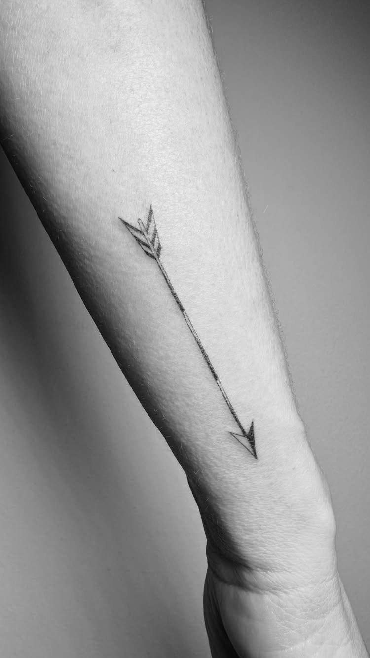 26 Small Pretty Tattoos for Butterflies, Stars, and More 5 Small arrow tattoo on the inner forearm of a person in black and white.