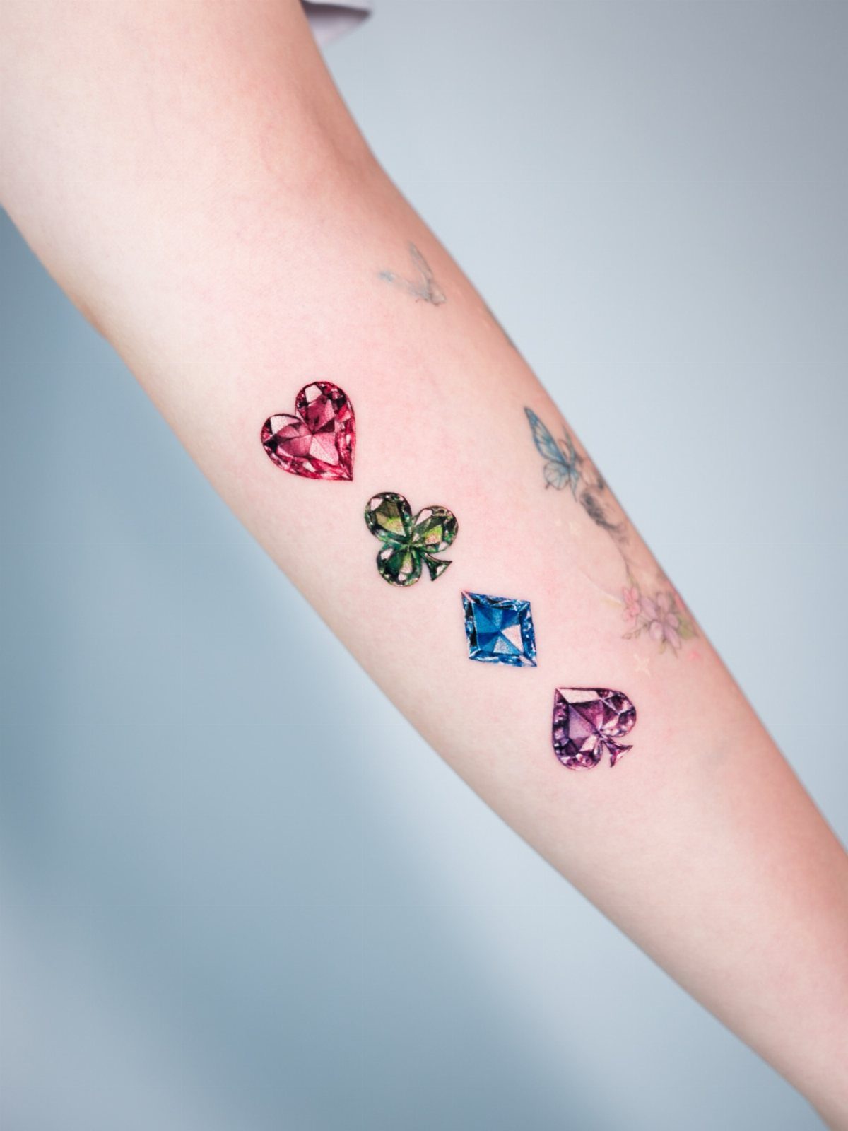 26 Small Pretty Tattoos for Butterflies, Stars, and More 20 Four colorful gemstone tattoos in various shapes and colors on a person's forearm.