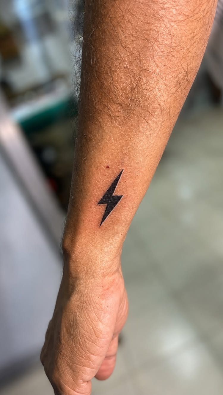 26 Small Pretty Tattoos for Butterflies, Stars, and More 23 Small black lightning bolt tattoo on a person's inner wrist and forearm.