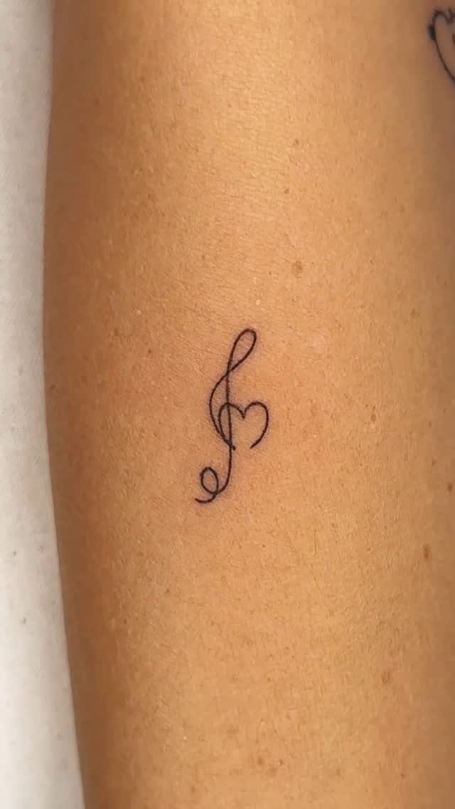 26 Small Pretty Tattoos for Butterflies, Stars, and More 18 Small black ink tattoo of a musical note with a heart on skin