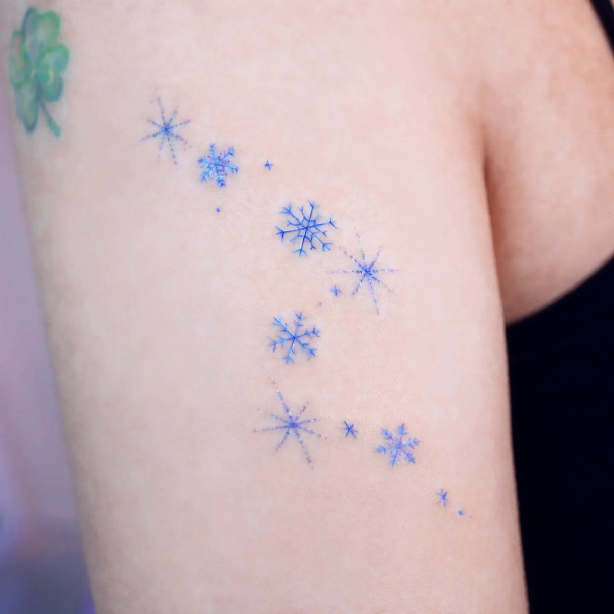 26 Small Pretty Tattoos for Butterflies, Stars, and More 11 Small blue snowflake tattoos of different sizes on a person's arm.