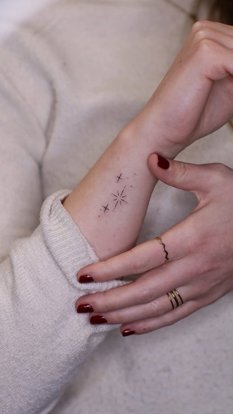 26 Small Pretty Tattoos for Butterflies, Stars, and More 7 Three tiny black star tattoos on a person's inner wrist with red nails.