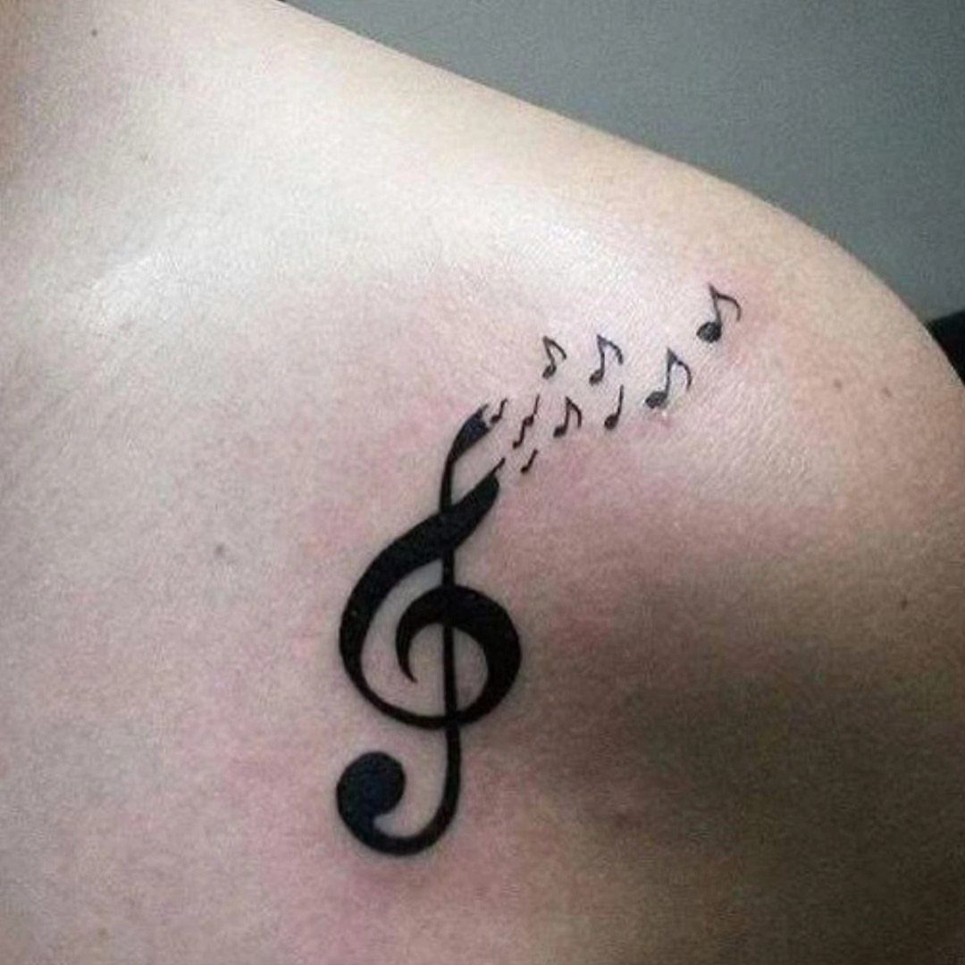 Treble clef and musical notes tattoo on a person's shoulder