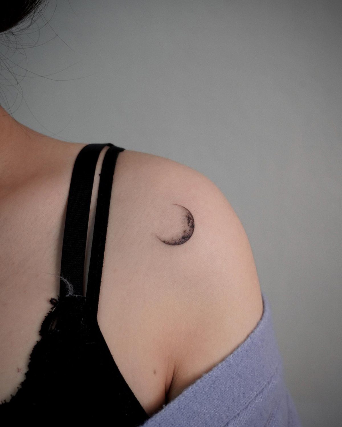 Crescent moon tattoo on the upper arm and shoulder of a person.