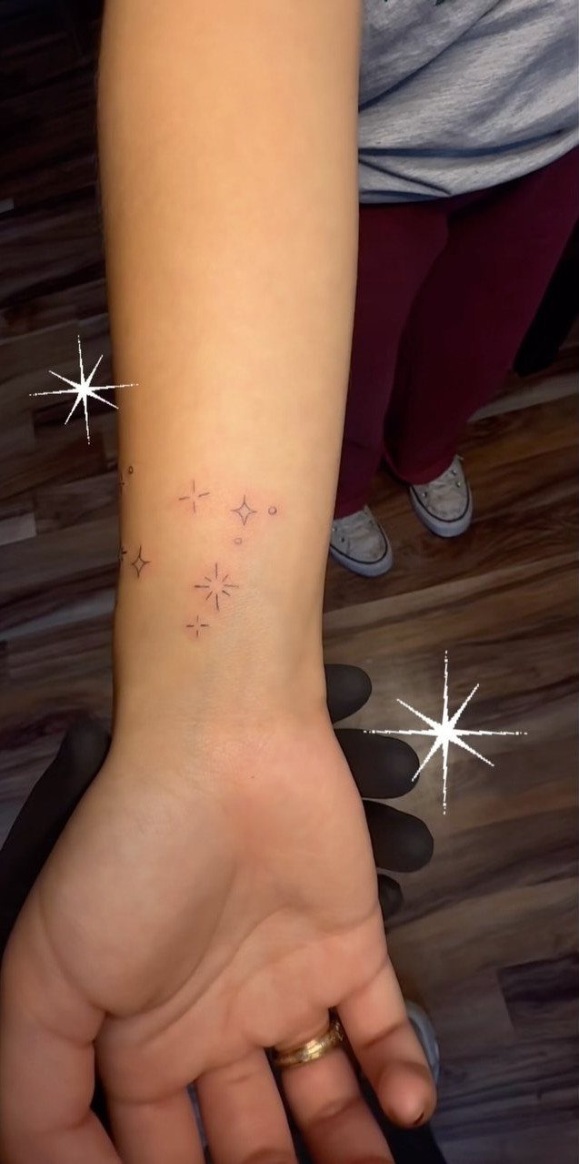 Small four-pointed star tattoos on a person's inner wrist and forearm.