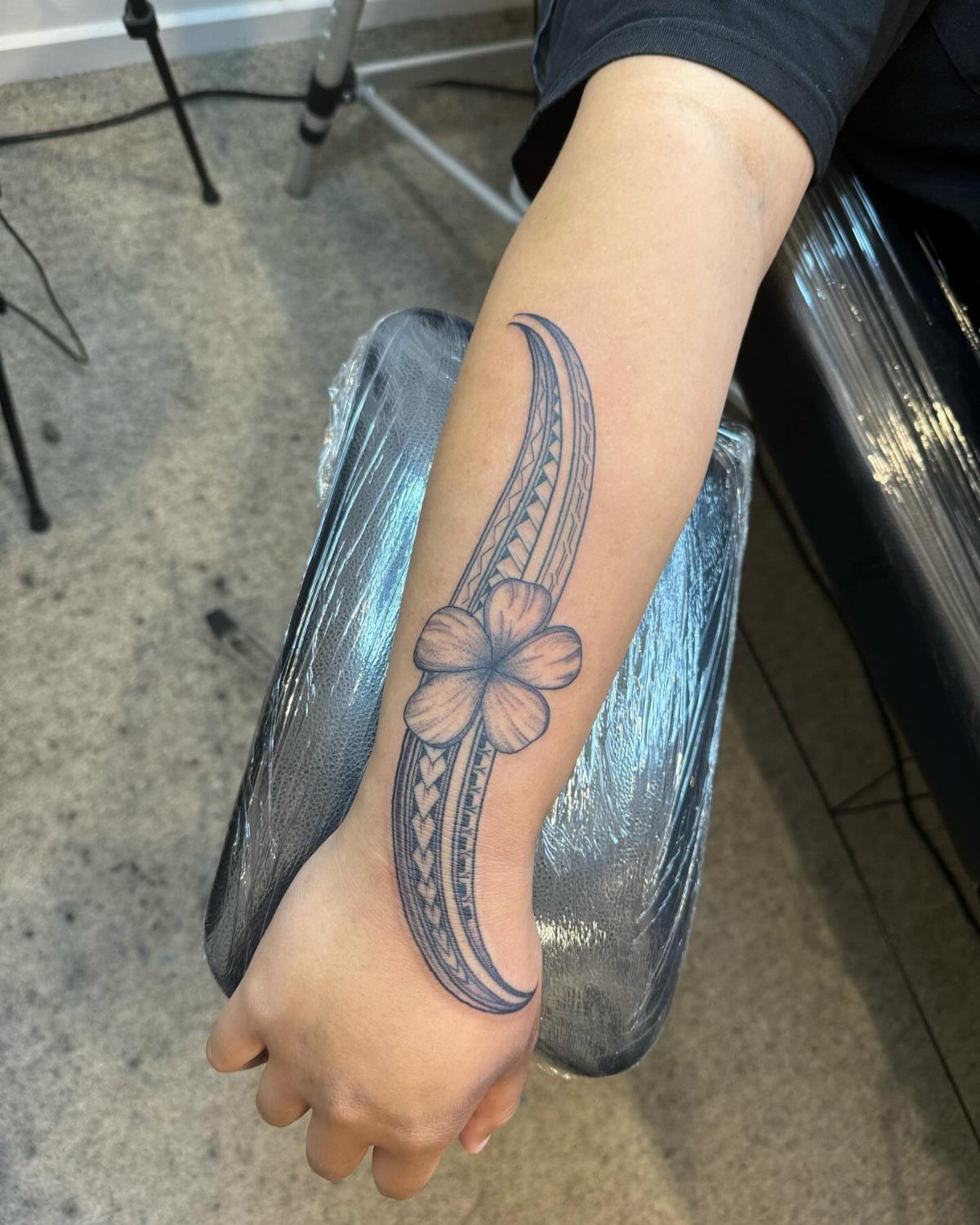 Tribal style tattoo with a flower on a person's forearm