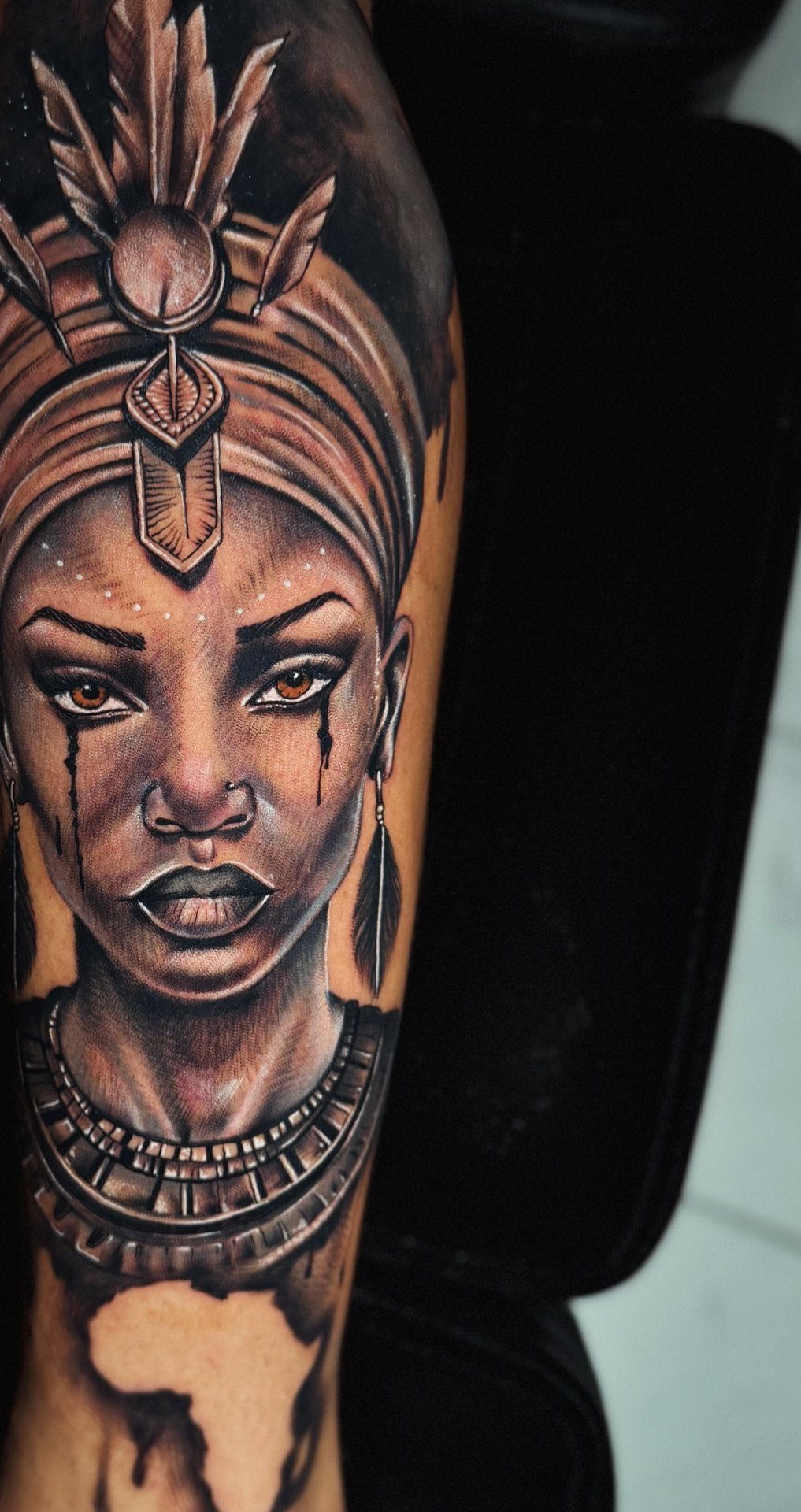 Tattoo of a woman with traditional African headwear and jewelry on an arm