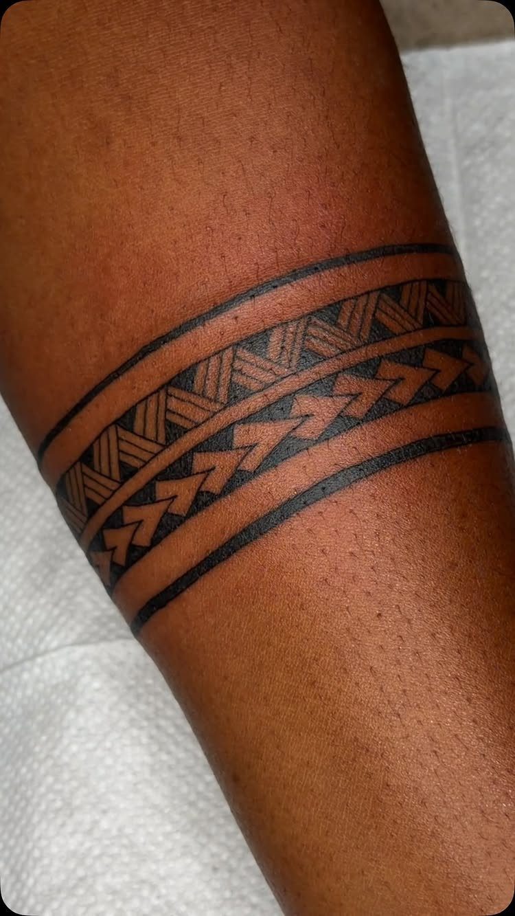 Tribal band tattoo with geometric patterns on a person's brown arm