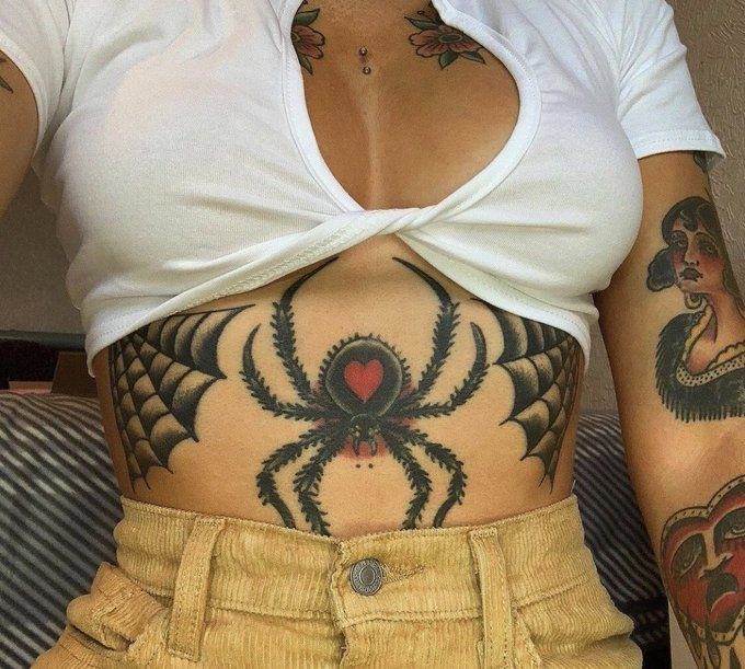 Spider tattoo with a red heart on its back on a person's stomach.