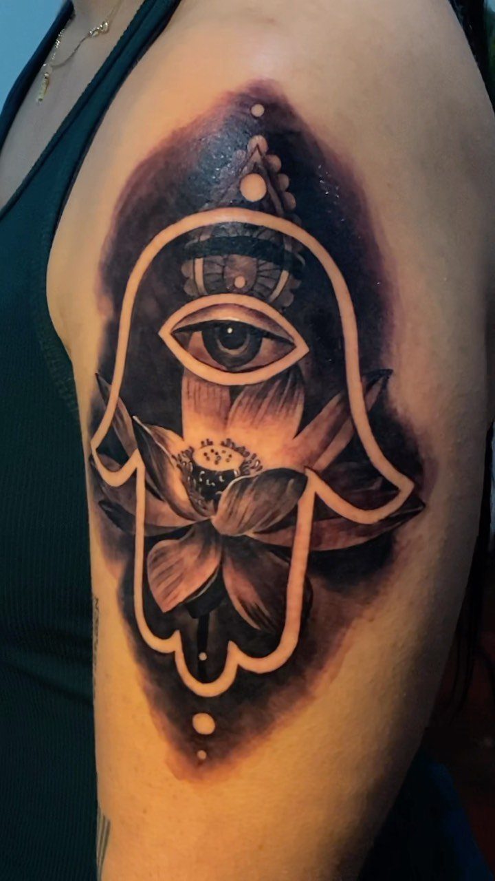 Hamsa hand tattoo on an arm featuring an eye and a lotus flower