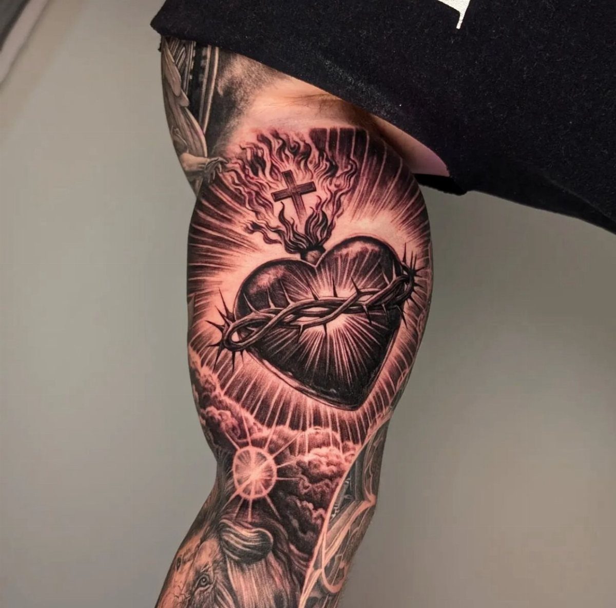 Sacred Heart tattoo with crown of thorns and flames on a person's arm.