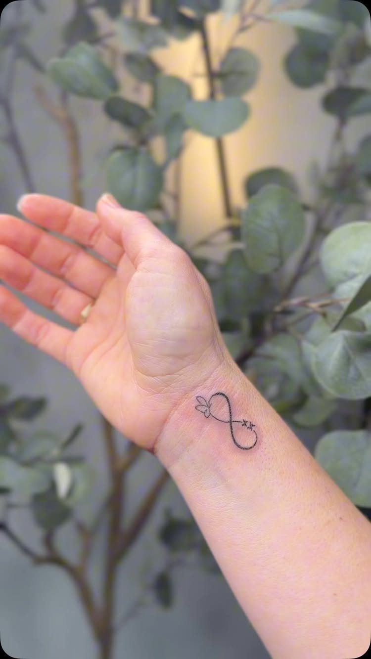 Infinity symbol tattoo with a small heart on a person's inner wrist