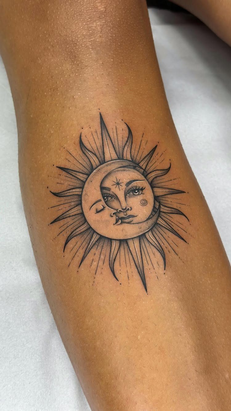 Sun and crescent moon tattoo with faces on a person's leg