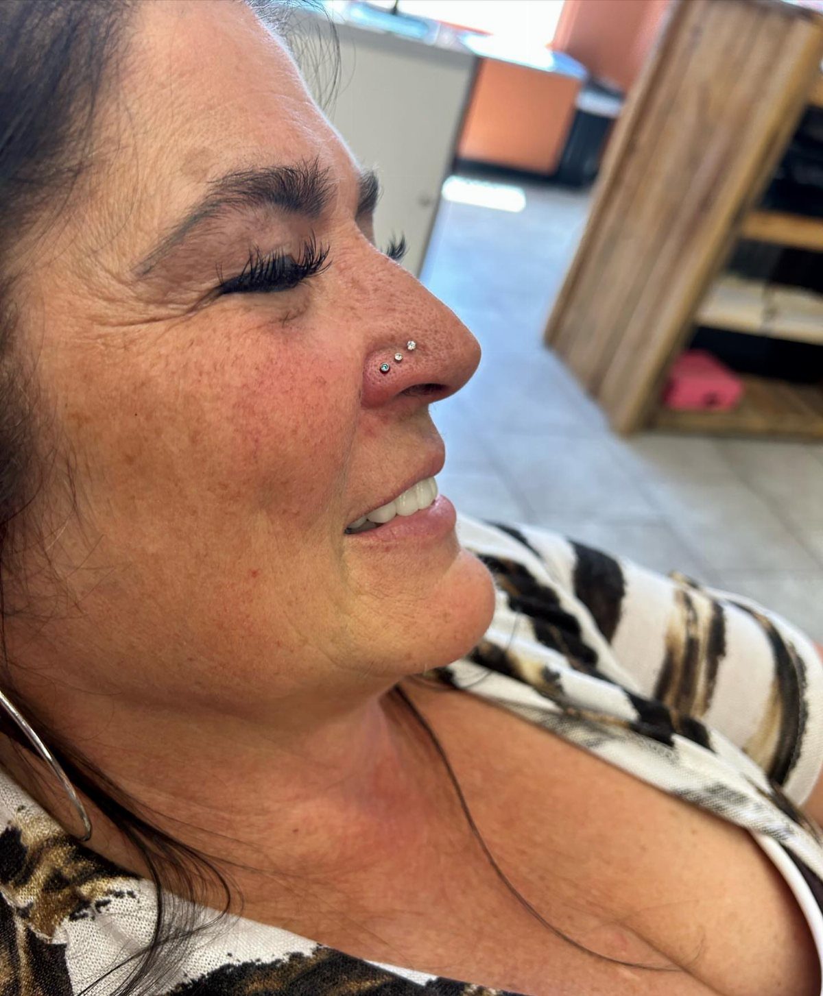 Woman with two silver stud piercings stacked on the side of her nose.