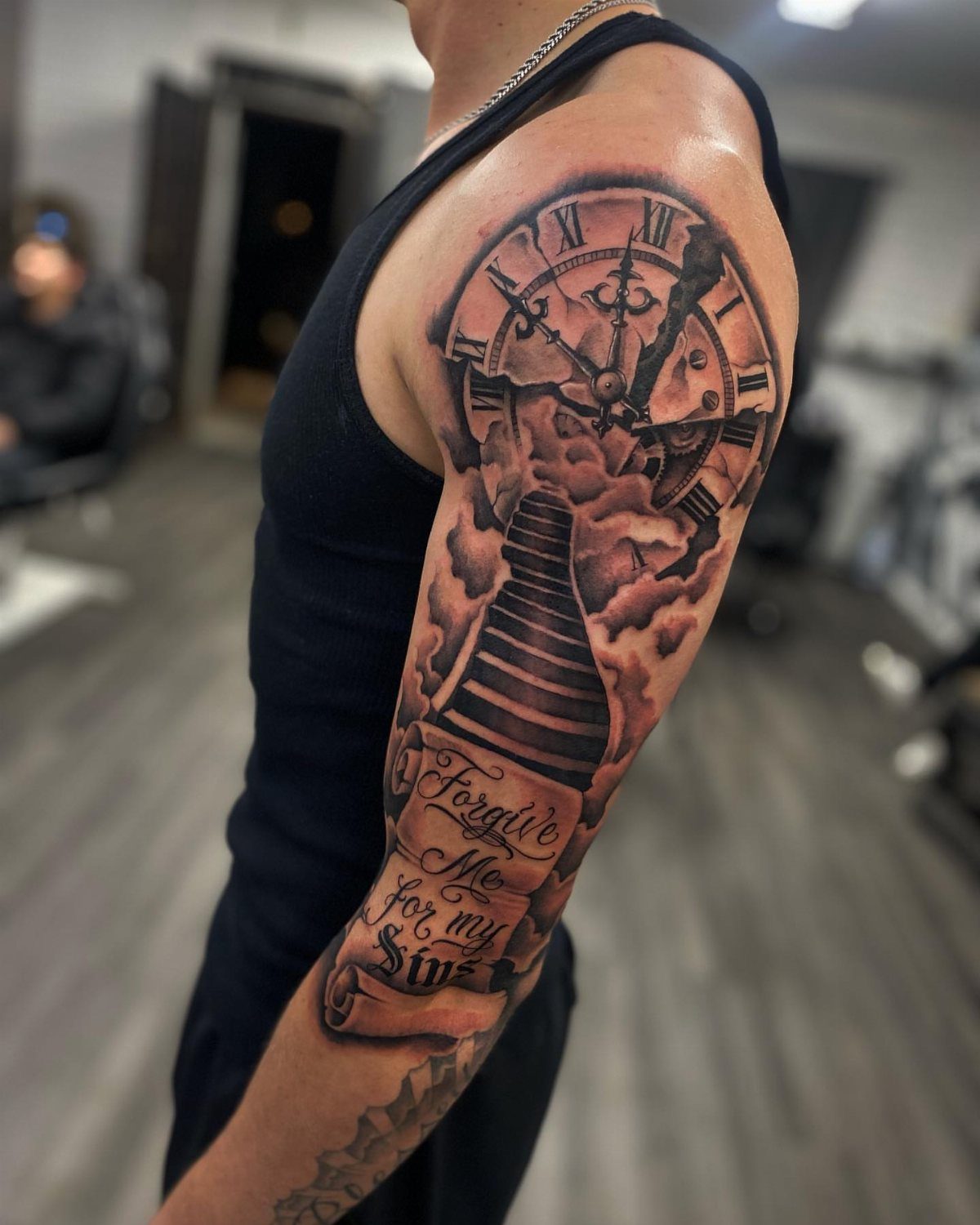 Broken clock tattoo on an arm with stairs and a religious scroll.
