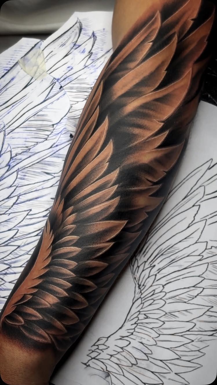 Detailed feathered wing tattoo on a person's arm next to a design sketch.