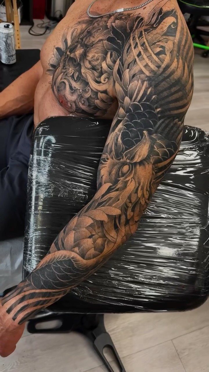 Detailed black and grey Japanese sleeve tattoo featuring a dragon on a man's arm.