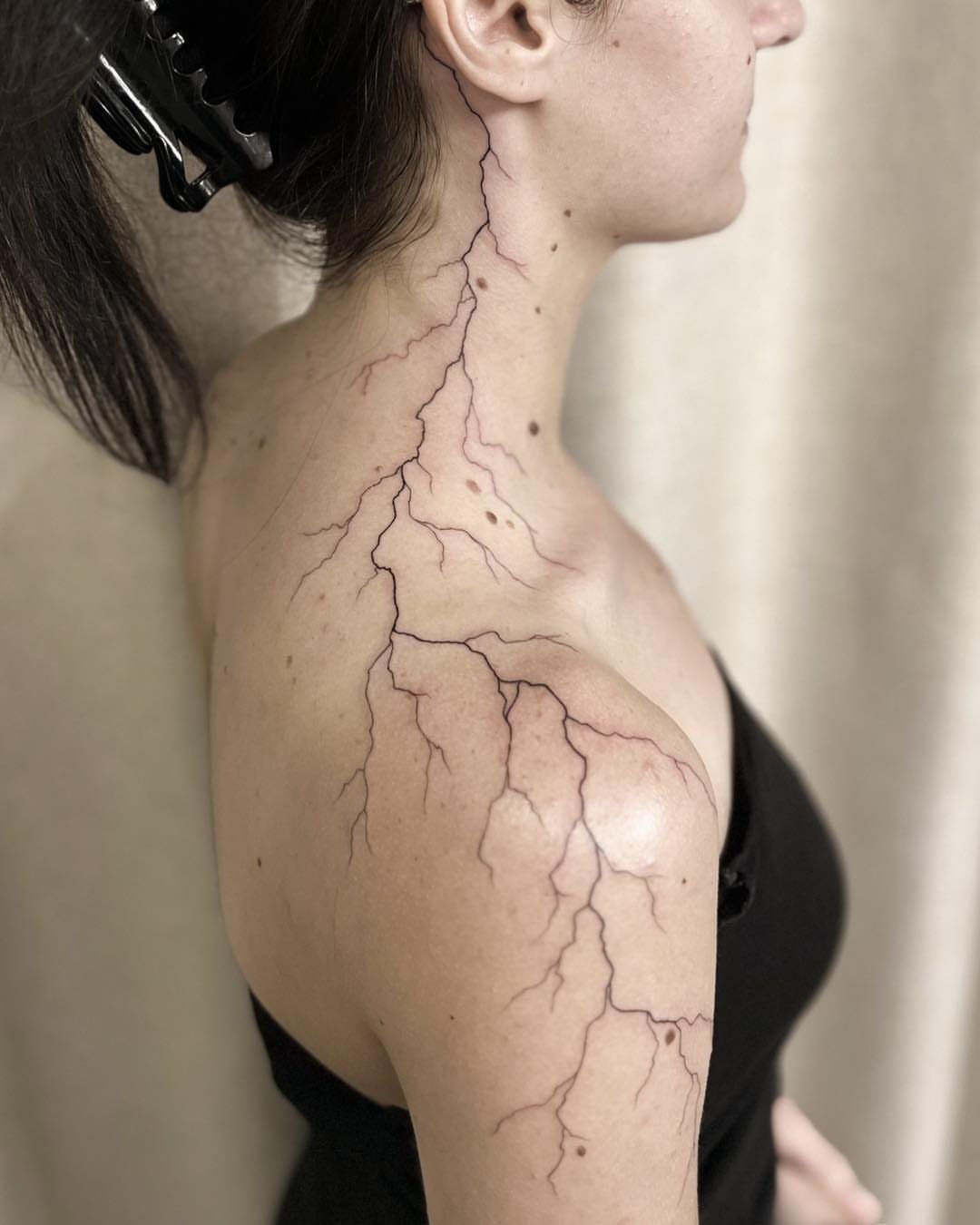 Lightning bolt tattoo extending from the neck down across the shoulder and upper arm.