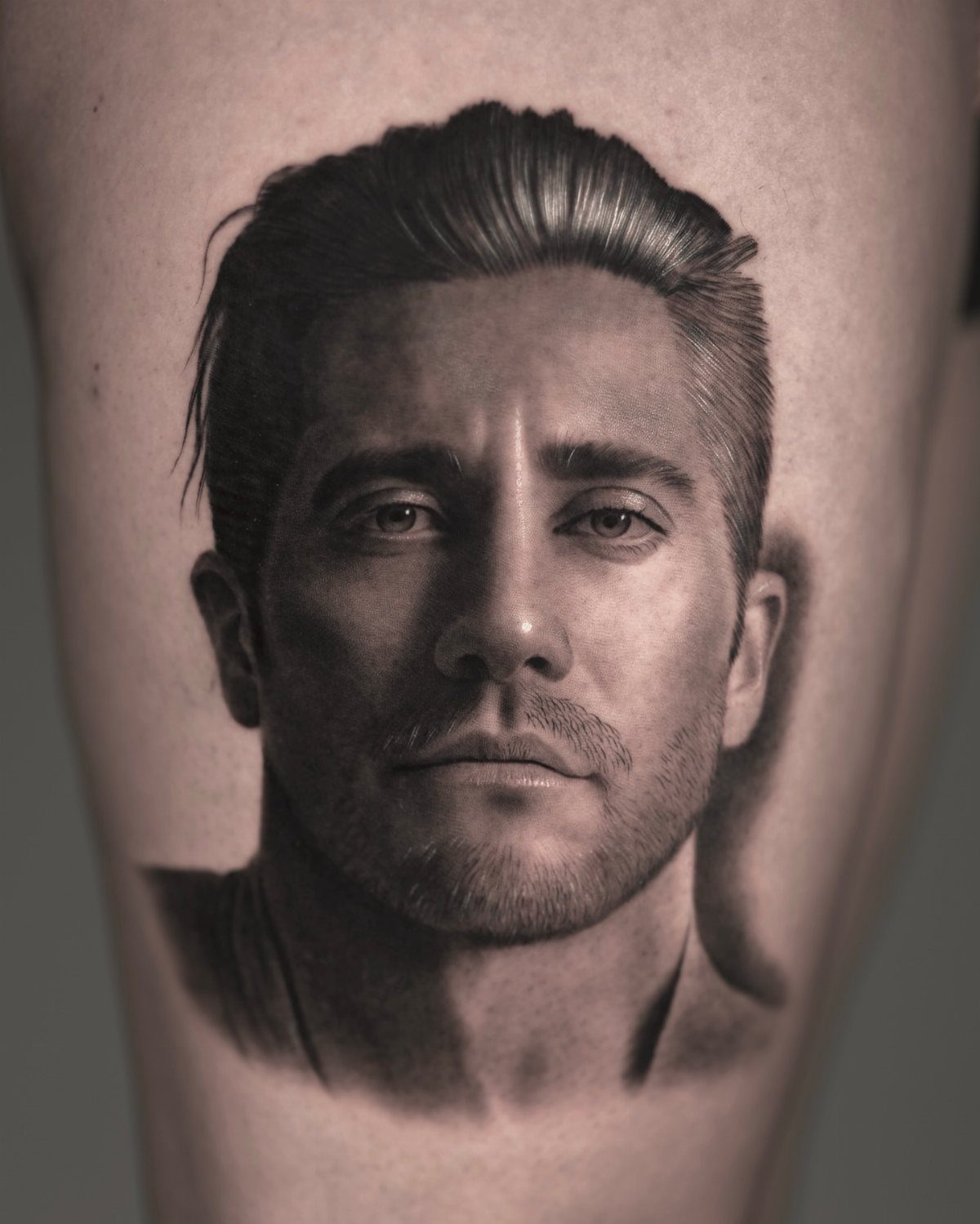 Realistic portrait tattoo of a man's face on a person's arm.