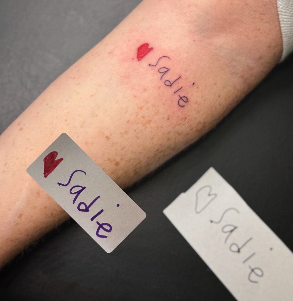 Tattoo of the name Sadie and a red heart on a forearm.