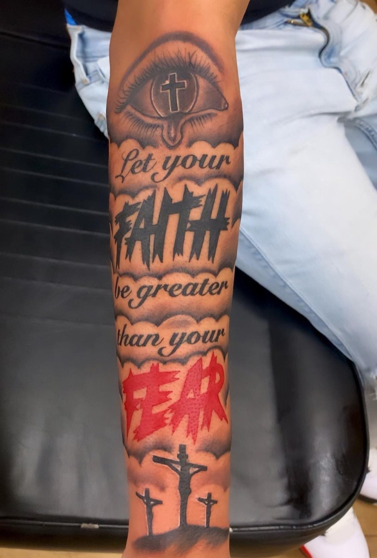 Forearm tattoo with text Let your faith be greater than your fear and crosses.