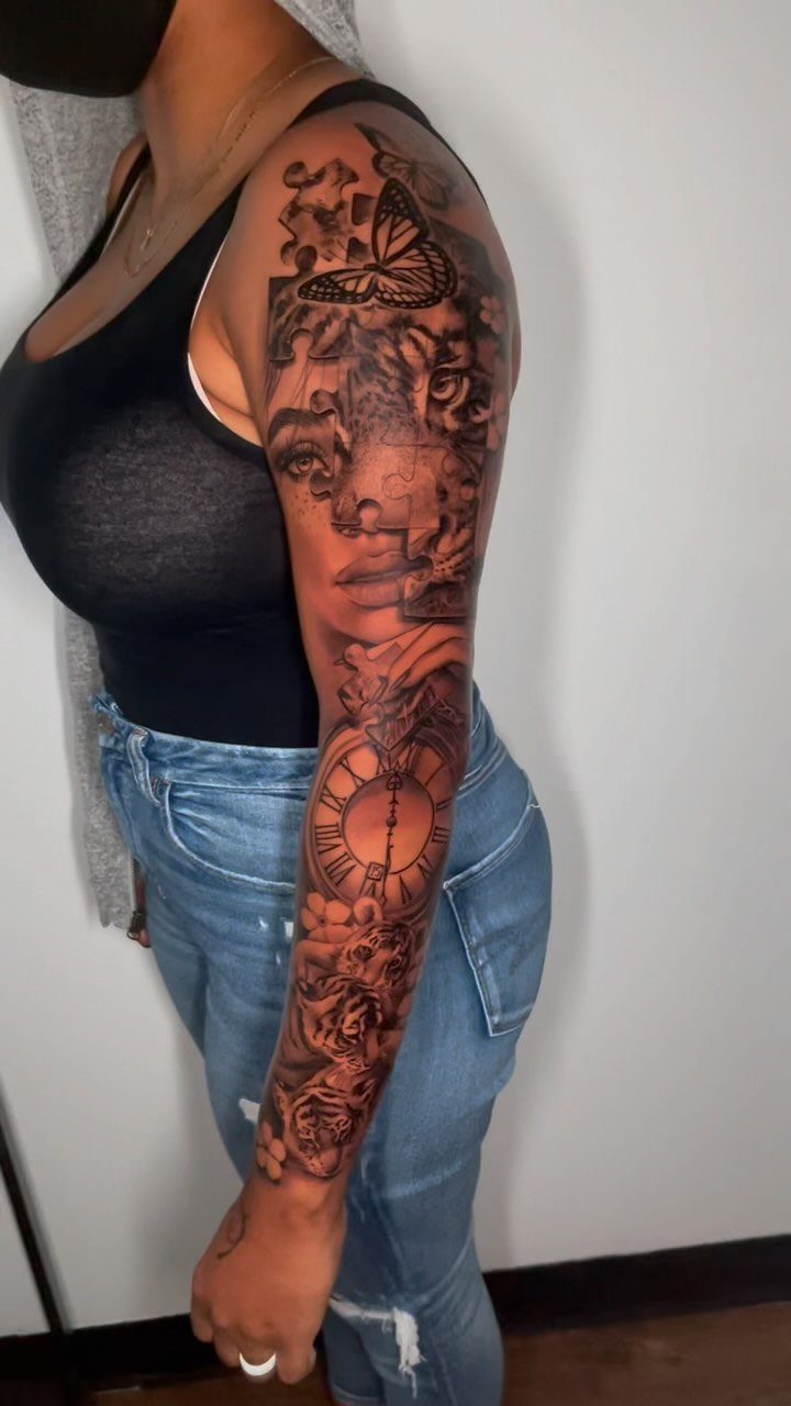 Full sleeve black and grey tattoo on dark skin featuring a face and clock.