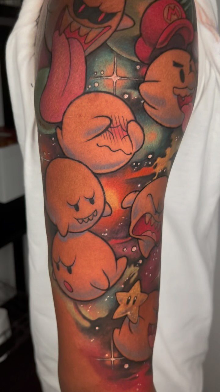 Colorful cartoon ghost tattoos on a person's dark-skinned arm with cosmic backgrounds.