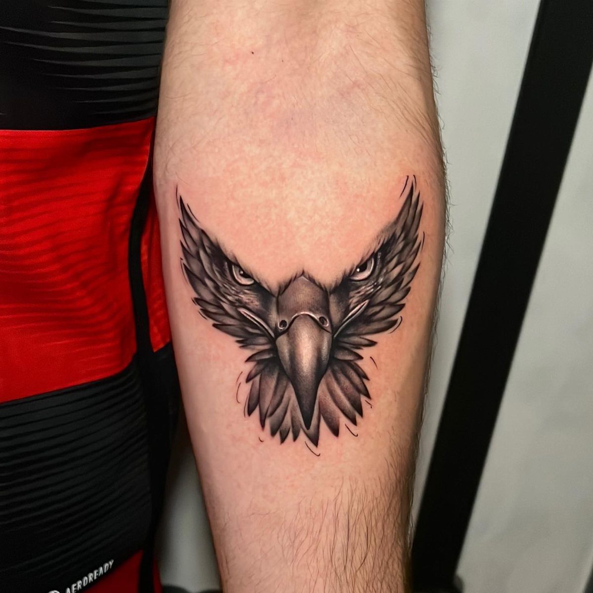 Eagle tattoo on a forearm featuring a detailed head and spread wings.