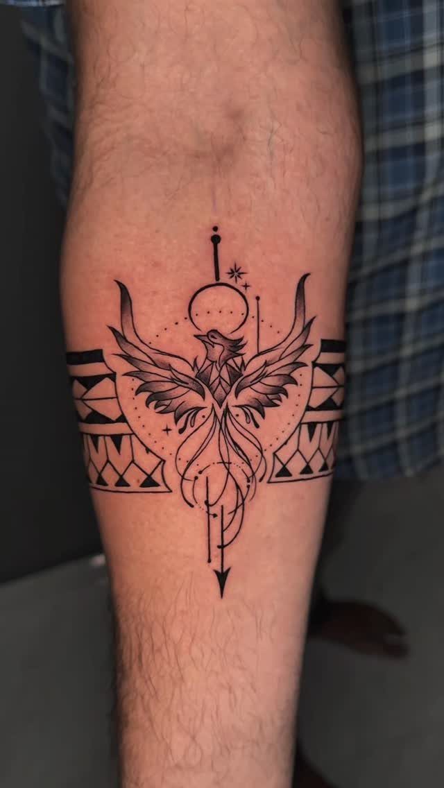 Phoenix tattoo with geometric elements and an arrow on a person's forearm.
