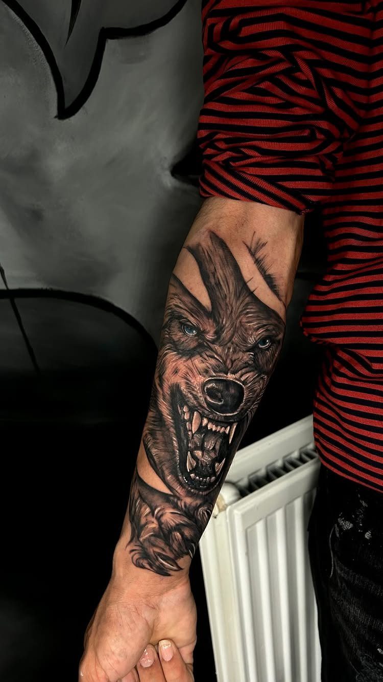 Detailed black and grey wolf tattoo on a person's forearm showing a snarling expression.