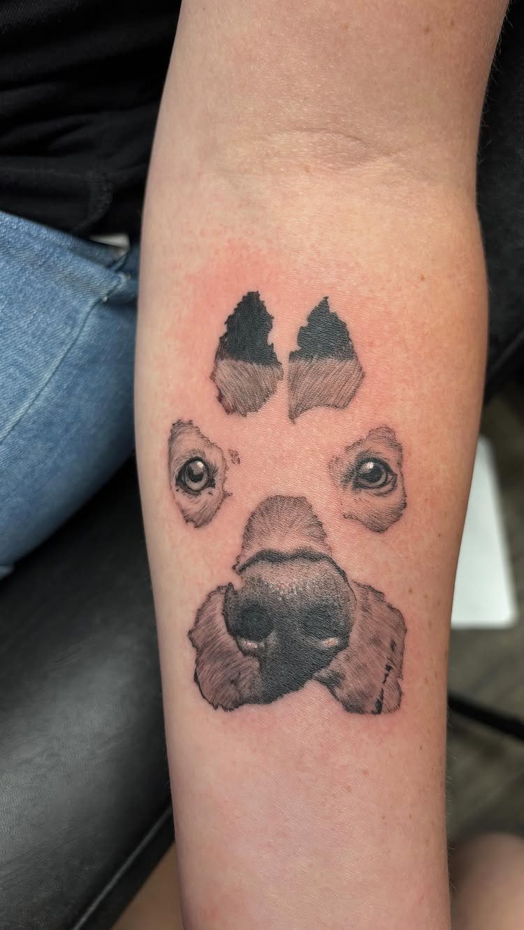 Dog nose and eyes tattoo arranged in the shape of a paw print.