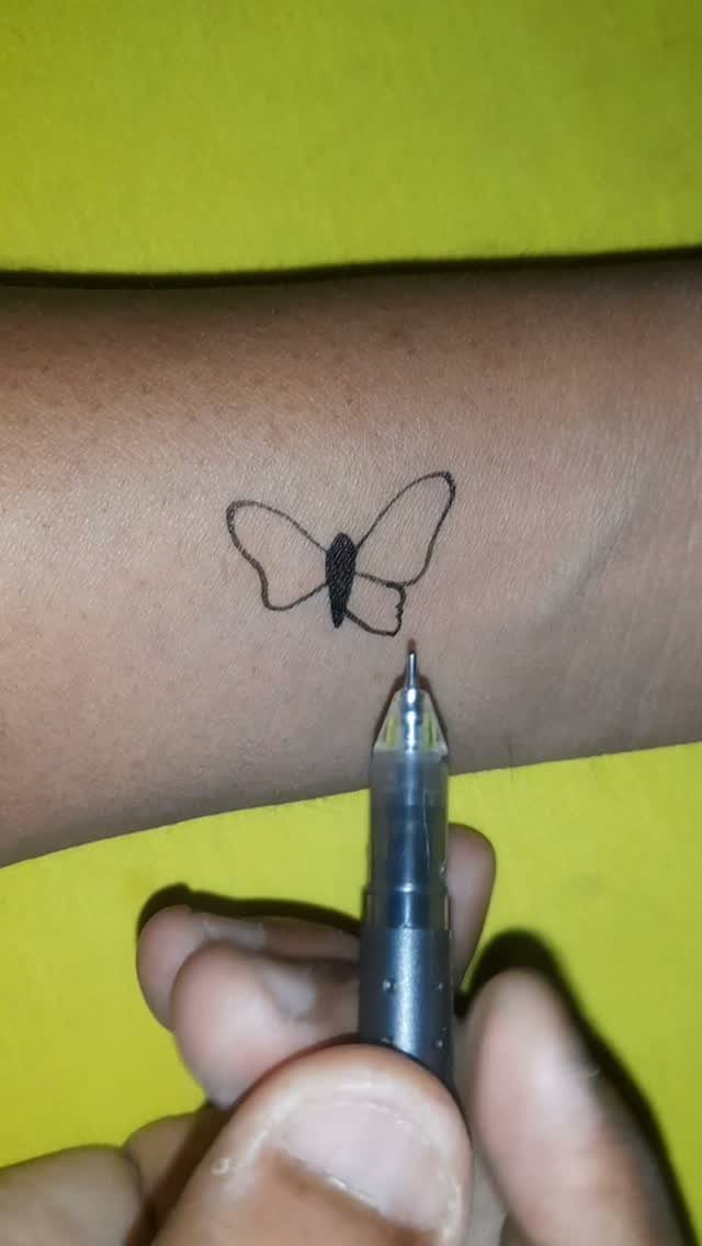 Butterfly drawing on a forearm being created with a black ink pen