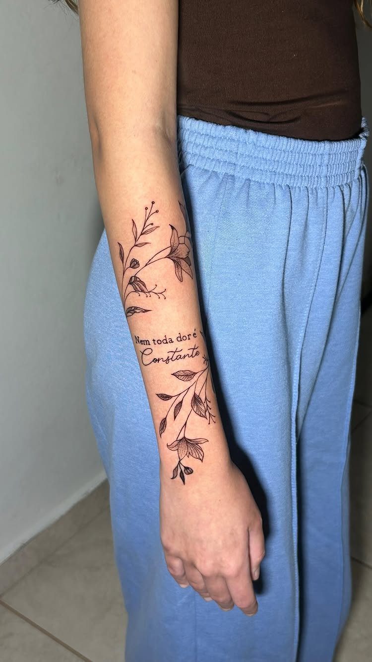 Floral patterns and cursive text drawn in black ink on a person's forearm.