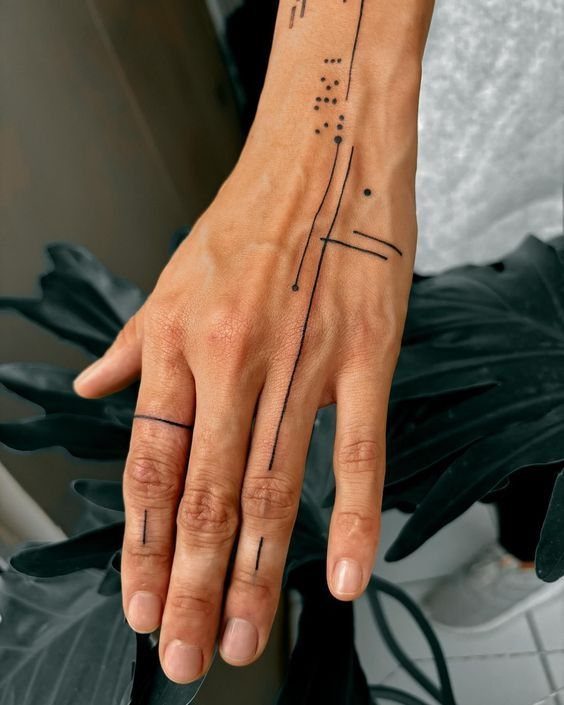 Hand and wrist with black ink geometric lines, dots, and finger bands.