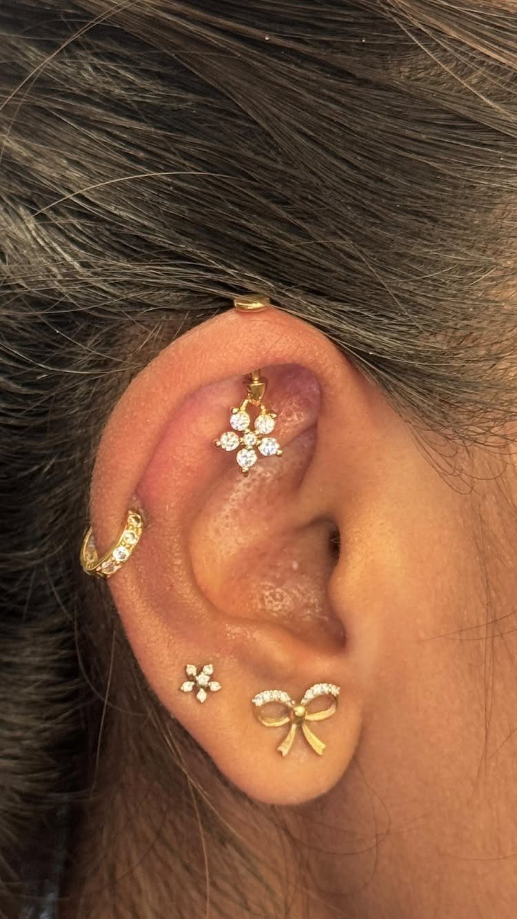 9 Upper Cartilage Piercing Ideas, Jewelry, and Aftercare 5 Ear with gold jewelry including a flower stud in the upper cartilage piercing.