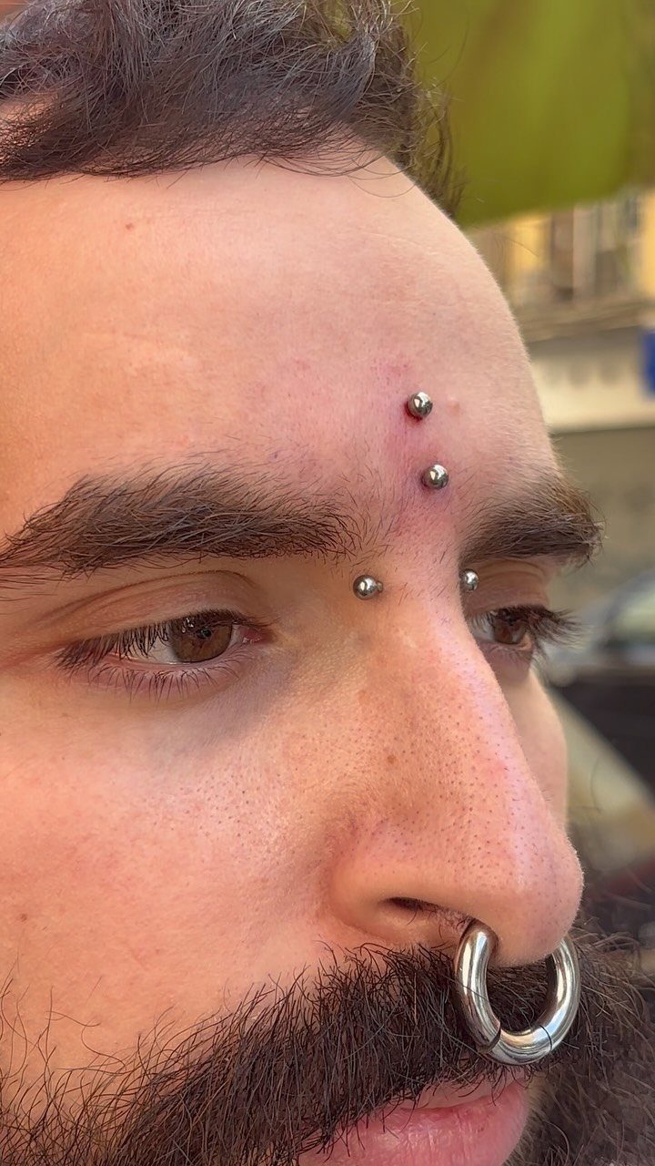 Vertical Bridge Piercing: 7 Jewelry Ideas and Styles 3 Man with three vertical silver ball piercings on the bridge of his nose.