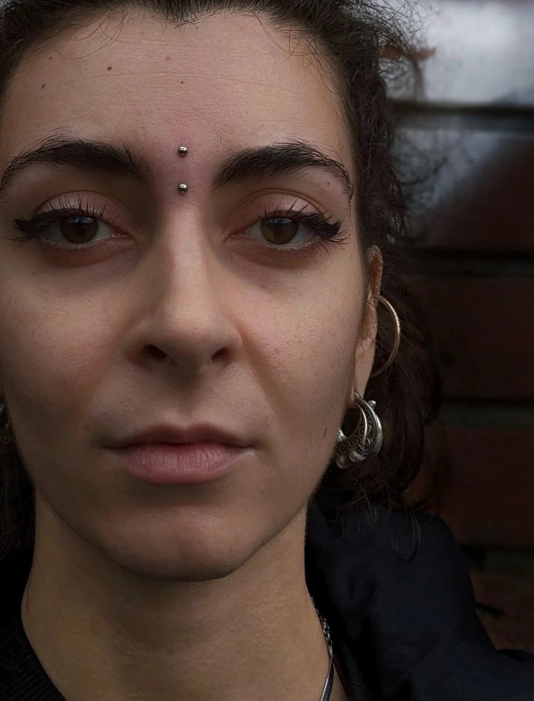Vertical Bridge Piercing: 7 Jewelry Ideas and Styles 1 Person with a vertical bridge piercing and silver hoop earrings.