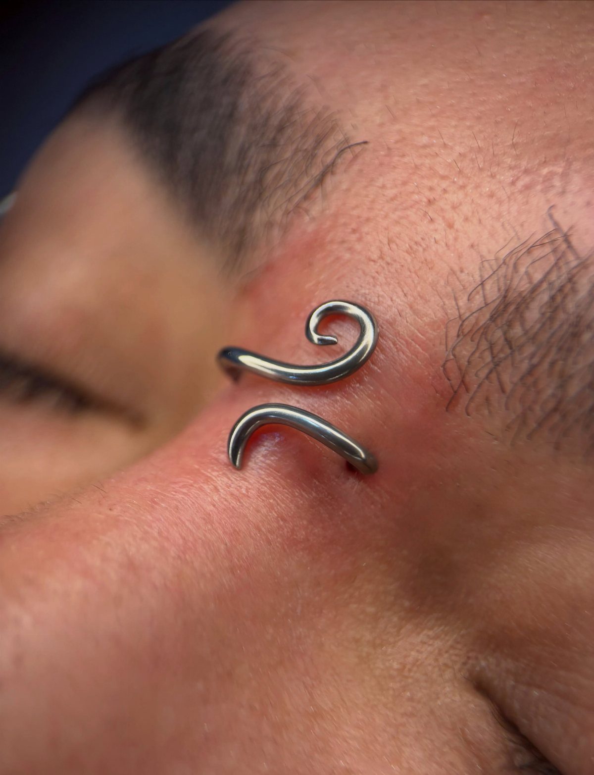 Vertical Bridge Piercing: 7 Jewelry Ideas and Styles 7 Vertical bridge piercing with silver spiral barbells on a person's nose bridge.