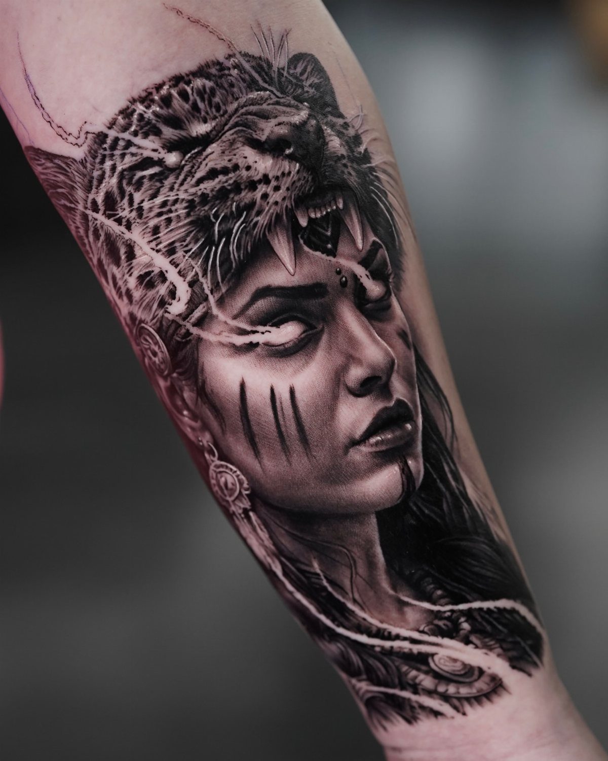 Realistic black and grey tattoo of a warrior woman wearing a leopard headdress.