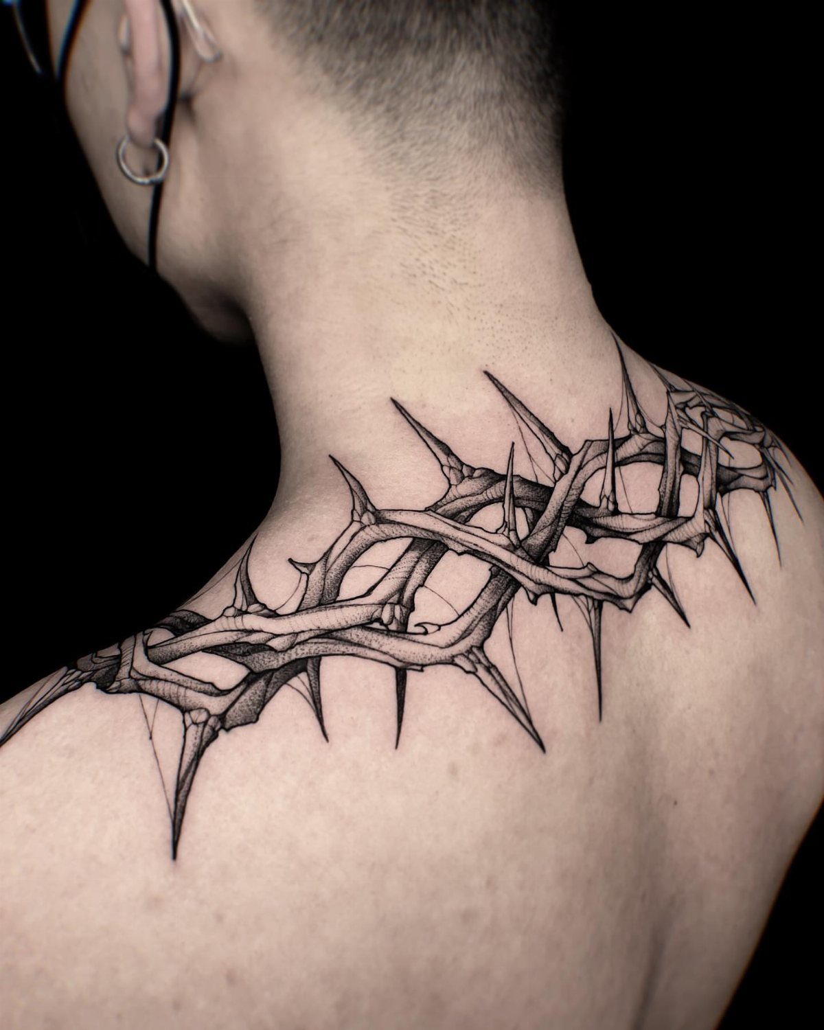 5 Witchy Neck Tattoos for Moon, Moth and Raven Lovers 2 Thorny vine tattoo wrapping around the back of a person's neck and shoulders.
